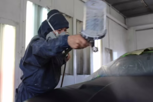 Auto body technician applying paint at Toyo Tec Collision Center in Cypress, TX